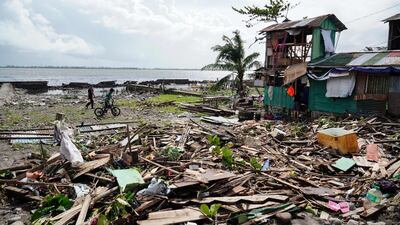 Residents walk past a house damaged during Typhoon Phanfone in Tacloban, Leyte province, in the central Philippines, on December 25. AFP