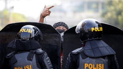 A protester gestures as police officers stand guard at a barricade in Jakarta, Indonesia. Reuters