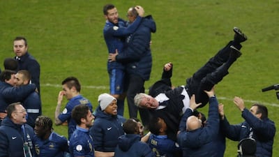 The French squad lift Didier Deschamps into the air following their World Cup qualification on Tuesday night. Thibault Camus / AP