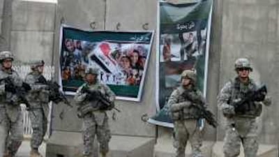US soldiers walk past election posters outside the former Saddam general hospital in Mosul yesterday. In Iraq's most violent province, the election could help bring peace or stoke fresh conflict between Arabs and Kurds.