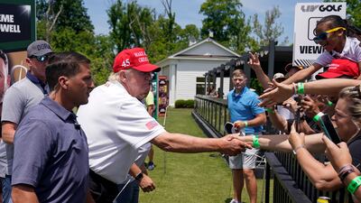 Mr Trump shakes hands with fans. AP