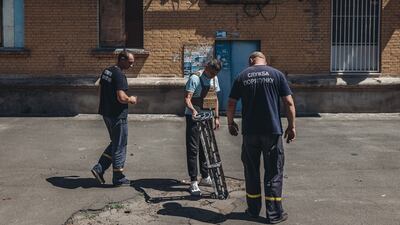 Emergency service workers look at the remains of a cluster bomb in Bakhmut, Ukraine. Getty Images