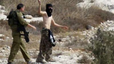 An Israeli soldier, left, tries to hold back a Jewish settler, centre, from disrupting Palestinian farmers harvesting olives in the West Bank village of Izmut near Nablus.