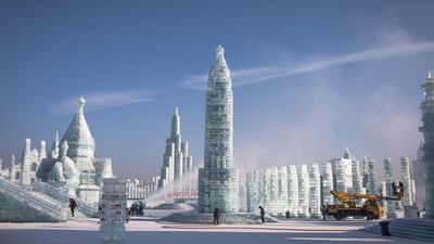 Workers use a machine to blow snow on the ice sculptures and perform other preparations. EPA