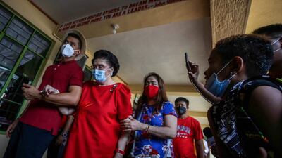 Imelda Marcos, mother of the Philippines presidential candidate Ferdinand Marcos Jr, is led through a polling station during the election in Batac, Ilocos Norte. AFP