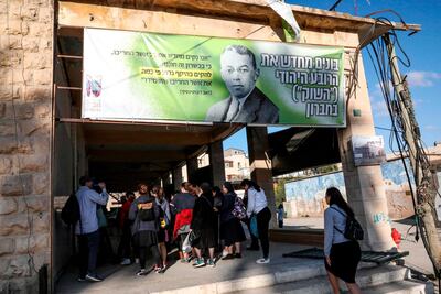 Israeli visitors walk below a banner showing the portrait of late Zionist leader Ze'ev Jabotinsky and text in Hebrew reading "Rebuilding the Jewish Quarter 'The Market' in Hebron" in the occupied West Bank. AFP