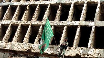 A Lebanese soldier stands in front of a building ravaged by the 1975-1990 civil war, alongside a flag for the Shiite Amal Movement.