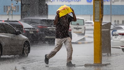 In Sharjah City at Clock Tower roundabout, this resident improvised with a reusable plastic bag to keep the rain off. Antonie Robertson/The National