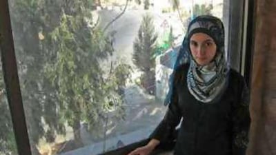 Salam Amira stands by the window where she filmed a bound and blindfolded Palestinian being shot by an Israeli soldier. The roadblock is seen at a distance.