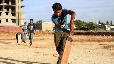 An Indian foreign worker bats a ball as he plays with others along a dirt pitch in Libya's eastern second city of Benghazi. AFP