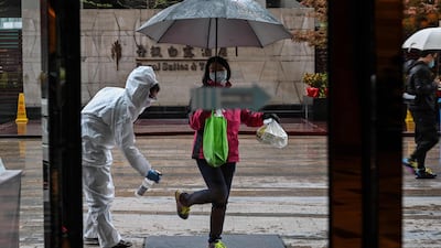 A hotel employee wearing a protective suit sprays disinfectant on an arriving guest, as a preventative measure against the COVID-19 coronavirus in Wuhan, China's central Hubei province, a day after travel restrictions into the city were eased following the outbreak. AFP