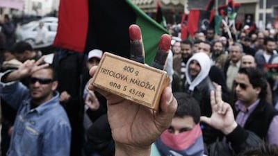 A Libyan man holds a box of cartridges as thousands gather for an anti-government protest in central Benghazi.