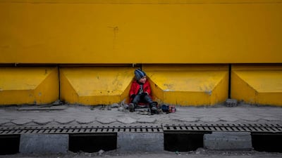 A young shoe-shiner sits as he waits for customers alongside a street in Kabul. AFP