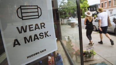 People walk past a sign reading "Wear a Mask" displayed in a shop window in Hudson, New York this week. Bloomberg