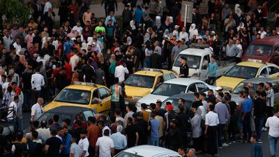 People wait at a junction in Damascus that has become a focal point for the relatives of political prisoners. AP