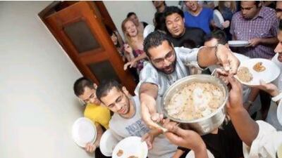 Cheered on by a hungry bunch, Shaneez Hameed carries another batch of foul to the serving table as the small but well-travelled group of friends prepare to enjoy a meal in Abu Dhabi. Silvia Razgova / The National