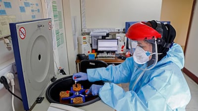 In this Sunday, March 1, 2020 photo, a paramedic works with a centrifuge to test blood samples taken from patients suspected of being infected with the new coronavirus, at a hospital in Tehran, Iran. Mizan News Agency via AP