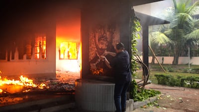 An anti-government protester vandalises a portrait of Bangladesh's founding father Sheikh Mujibur Rahman as others set the Bangabandhu Memorial Museum on fire in Dhaka. AFP
