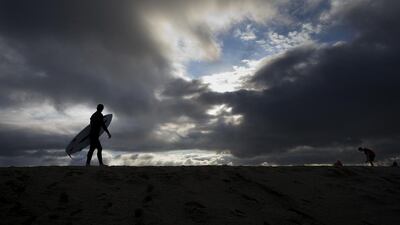 Surfer Bradley Domke walks along a sand berm as storm clouds gather overhead in Seal Beach, California. Jae C. Hong / AP Photo