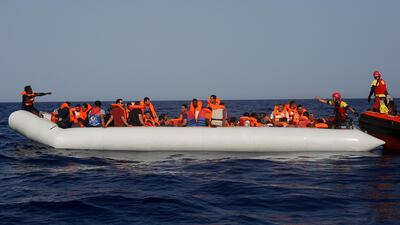 A lifeguard gives a thumbs-up to a migrant at the other end of a rubber boat in the middle of a rescue operation off the Libyan coast. AP Photo