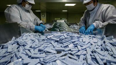 Sample testing devices used in diagnosing the Covid-19 novel coronavirus are checked on a production line as they are prepared to be included in testing kits for shipment. AFP
