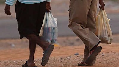 Labourers return home with bottles of spirits bought at an off-licence store on the outskirts of RAK.