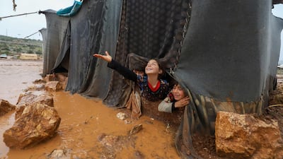 Children peek out of their flooded tent at the Umm Jurn camp for the displaced in Syria's Idlib province in January 2021. AFP