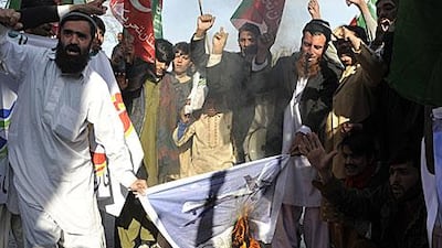 Pakistan protesters burn a banner with a US drone in Islamabad.