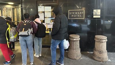 Migrants stand outside the Stewart Hotel in Midtown Manhattan, New York. Vacant hotels and office spaces have been turned into accommodation for arrivals. Adla Massoud / The National