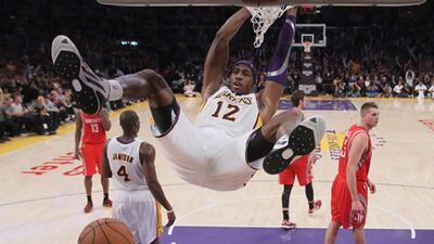 LA Lakers' Dwight Howard hangs onto the basket after dunking against Houston Rockets.