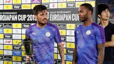 Manchester City's Raheem Sterling and David Silva, left, with the trophy after the match. Reuters