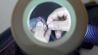 Javer Hussain hand stitches the details on a suit at the Parmar Tailors workshop. Reem Mohammed / The National