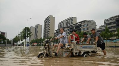 People wade through a flooded street following a heavy rain in Zhengzhou, in China's Henan province.