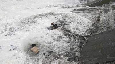A man, bottom, jumps into the water to rescue a woman, centre, who fell due to strong tidal waves on the Bay of Bengal coast at Gopalpur, Odisha. Biswaranjan Rout/ AP Photo