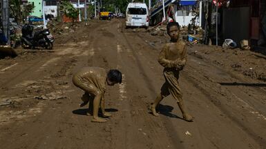 Children covered in mud play along the street in the aftermath of Typhoon Kalmaegi in Liloan, in the province of Cebu. AFP