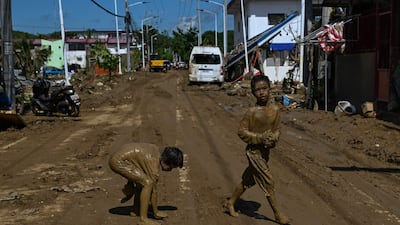 Children covered in mud play along the street in the aftermath of Typhoon Kalmaegi in Liloan. AFP