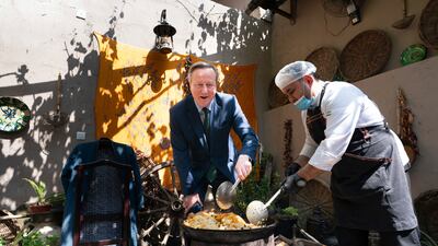 British Foreign Secretary David Cameron, left, stirs a pot of food at a restaurant in Tashkent, Uzbekistan. AP