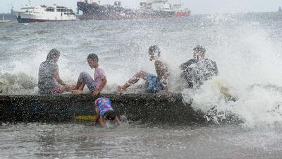 Residents along Manila Bay play in the waves created by the approachingTyphoon Noul yesterday. The Philippines government has suspended ferry services in affected areas and some domestic flights have also been cancelled. Jay Directo / AFP