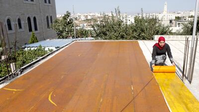 A woman spreads a plastic sheet used to make the traditional Arabic sweets, Malban, from grape molasses. EPA
