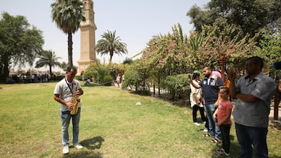 Iraqis film a man playing the saxophone in the park near al-Mutanabi Street in Baghdad. AFP