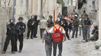 Palestinian school children walk past Israeli riot police during clashes with masked youths after an Israeli settler guard shot dead a Palestinian man overnight in Jerusalem. Ahmad Gharabli / AFP