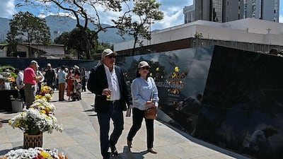 People walk next to a wall memorial in tribute to the victims of late Colombian drug lord Pablo Escobar at 'Inflection Park' in Medellin. AFP