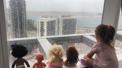 A child watches the UAE rains, accompanied by her toys. Courtesy of Hani Al Hussein