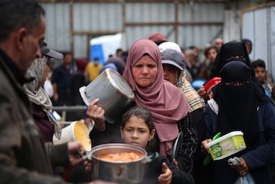 Displaced Palestinians stand in line to receive food being distributed by a charity kitchen at the Nuseirat refugee camp, in the central Gaza Strip on April 1, 2026. AFP