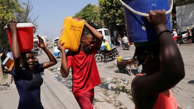 People carry water collected in containers in Port-au-Prince, Haiti, where gang violence has cut off food and fuel supplies. Reuters