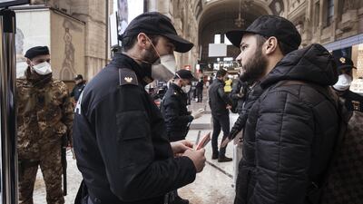 A police officer wearing a protective face mask speaks with a traveler at Centrale railway station in Milan, Italy. Bloomberg