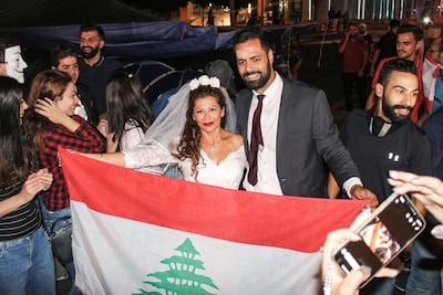 Malak Alaywe Herz, a woman who famously kicked the bodyguard of Education Minister Akram Chehayeb and became an icon in the current anti-government protests, poses for a picture in her wedding dress with a national flag alongside her newly-wed husband Mohammad after their marriage at Riad al-Solh square in the centre of the capital Beirut. AFP