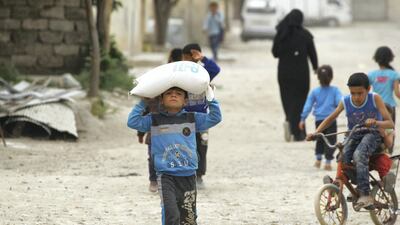A boy carries food aid given by UN's World Food Programme in Raqqa, Syria. Reuters