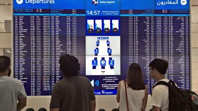 Passengers at Dubai International Airport look for news of their rescheduled flights. The National