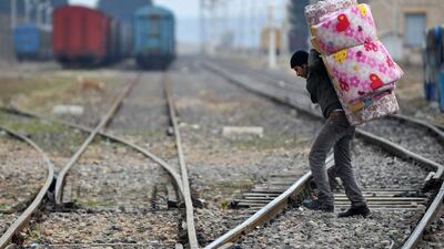 A Syrian refugee carrying his belongings passes over railway tracks after crossing the Syrian border on January 16, 2014 in Karkamis, near the town of Gaziantep, south of Turkey. AFP Photo